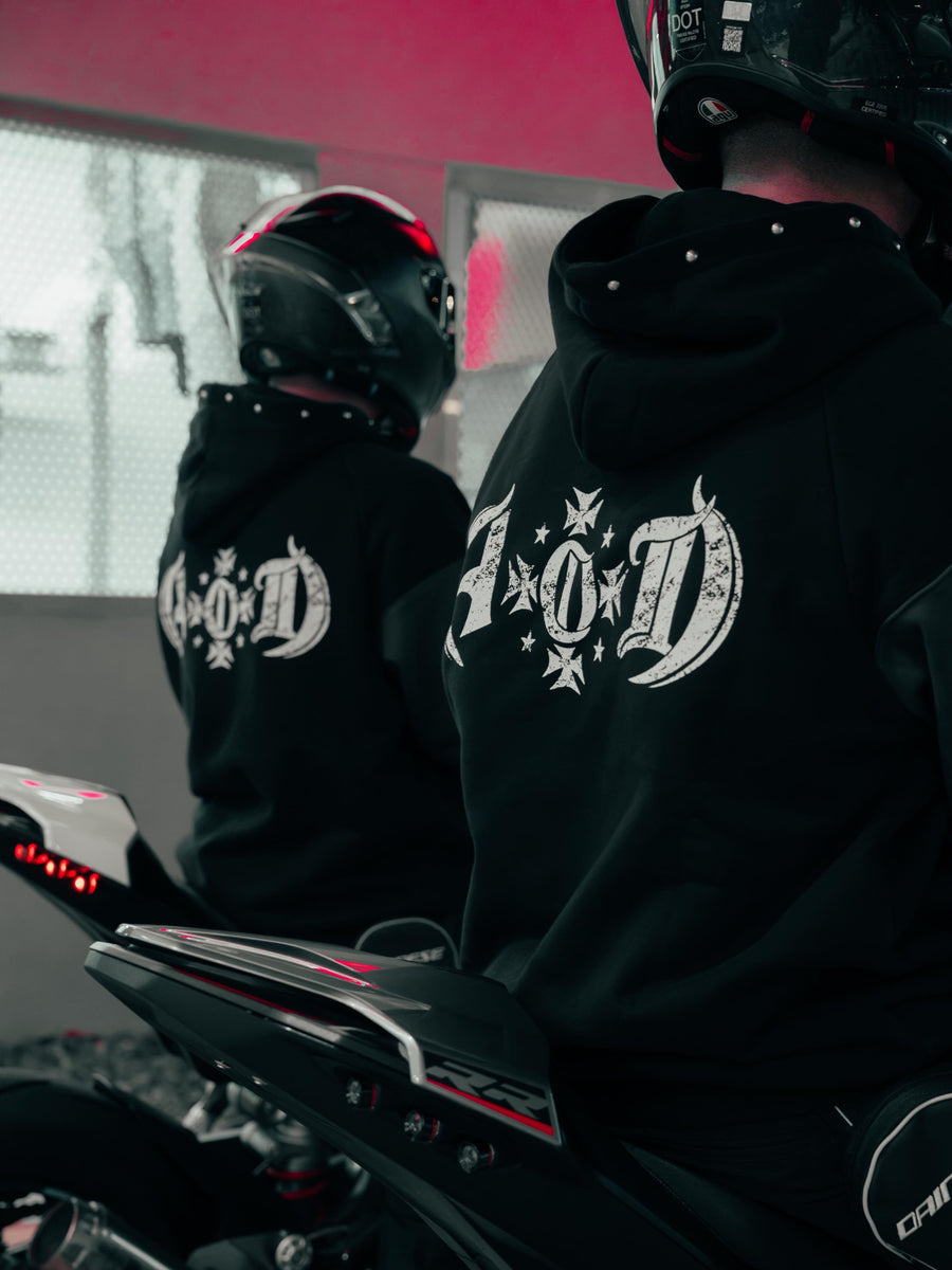 Two helmeted riders seen from behind wearing Adapt or Die hoodies